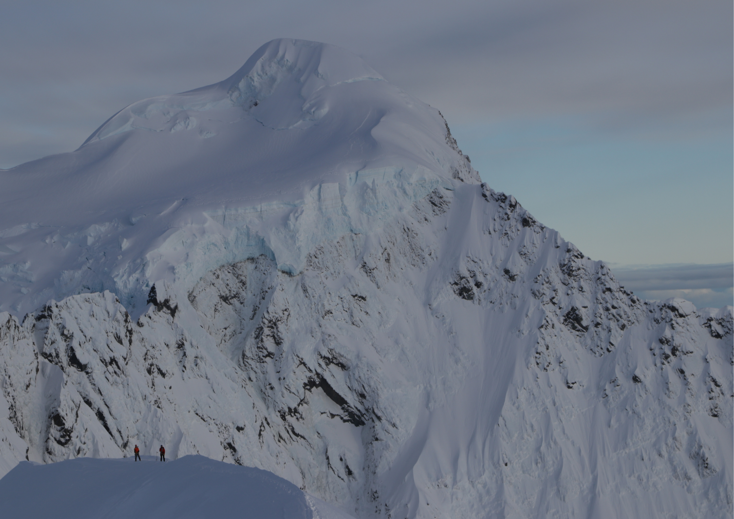 Dramatic view of a high alpine peak — Hochstetter Dome — with two climbers tiny below